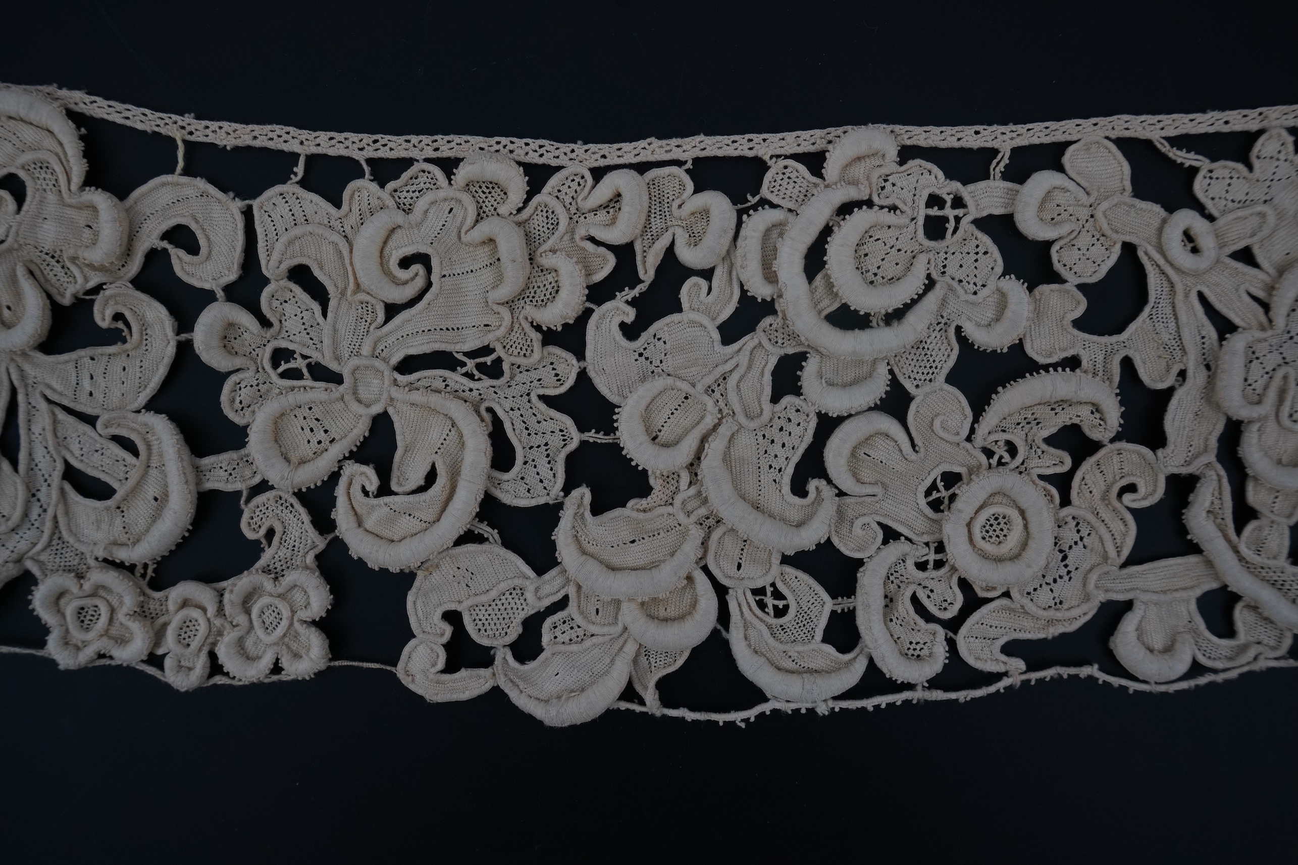 A length of 1660-1670 Italian Venetian Gros Point needle lace, this heavy needle lace was made with a wide cordonnet padded with wool, using close buttonhole stitch, to create large scrolling patterns in heavy relief, li